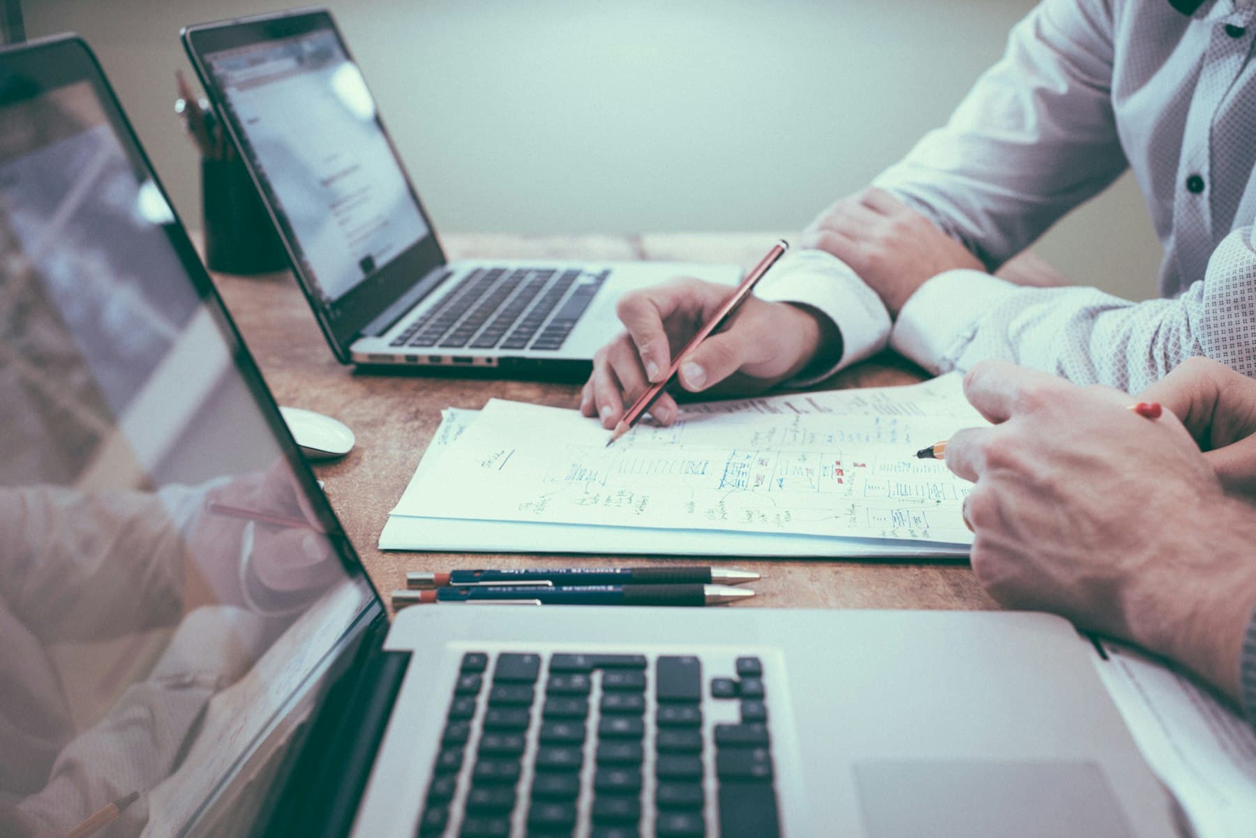 Two people working through figures together across laptops