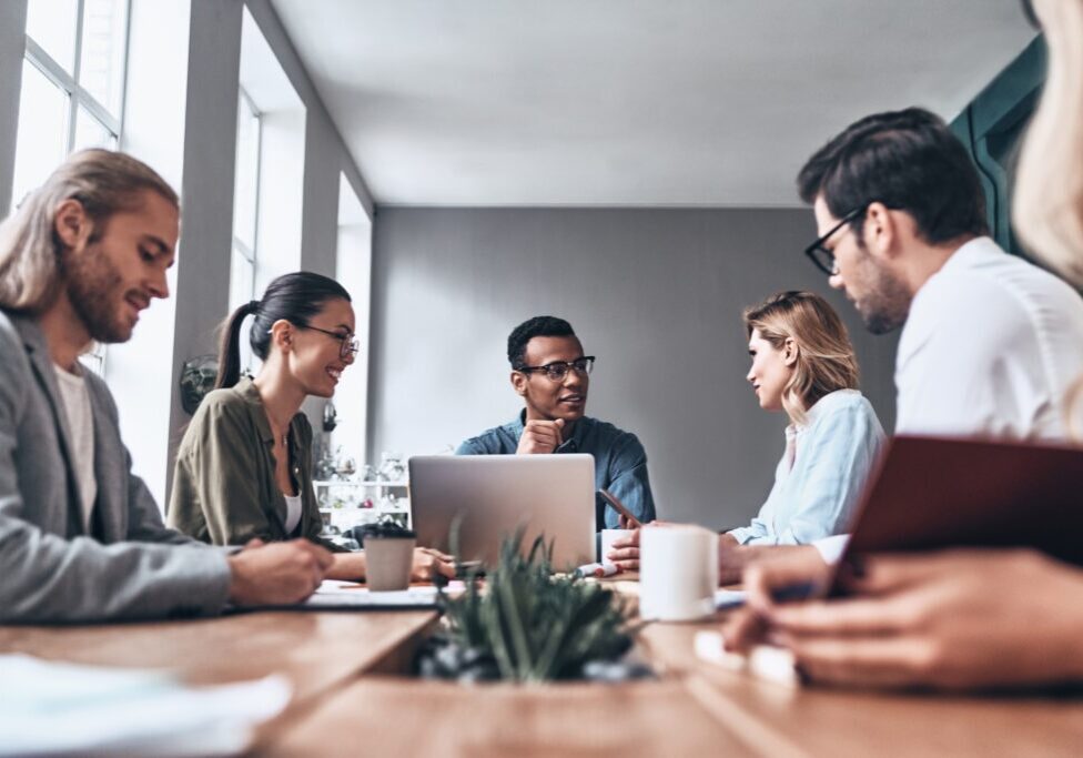 Group of young modern people in smart casual wear discussing business while working in the creative office